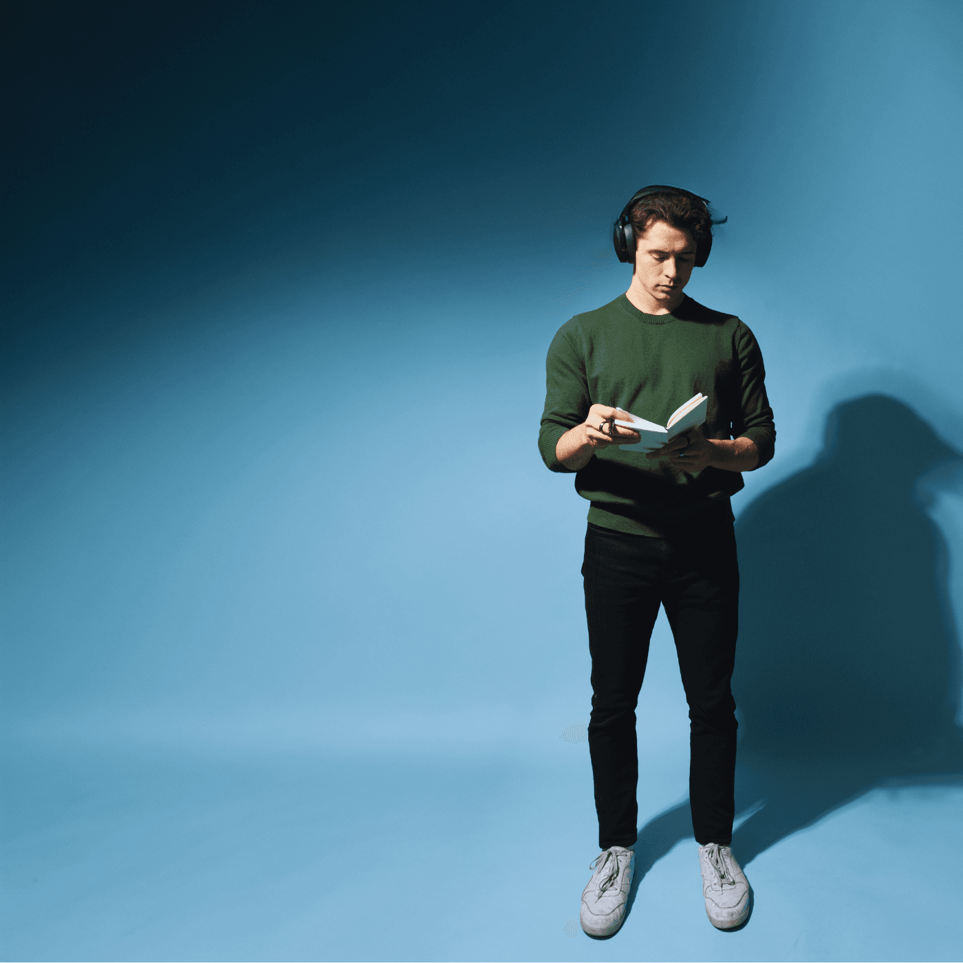 Maxwell Knowles reading with headphones against a blue backdrop